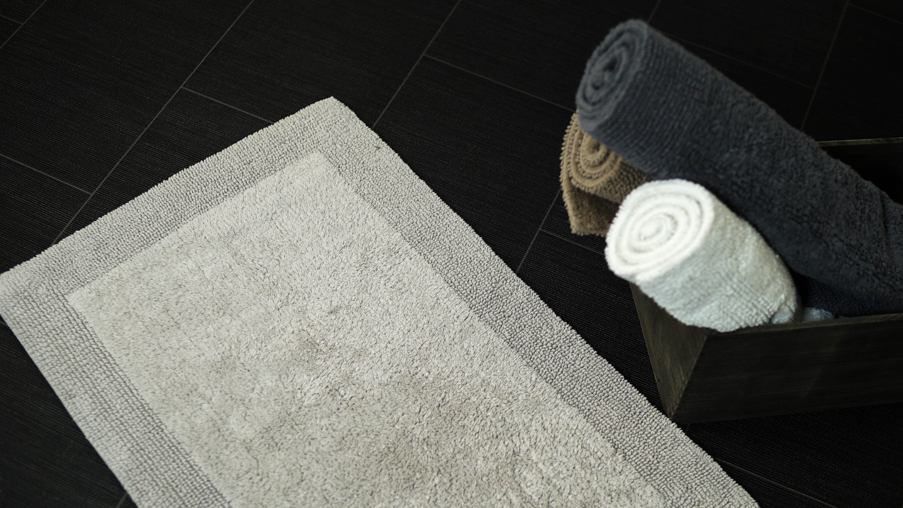 a luxury bath mat on a dark tile floor