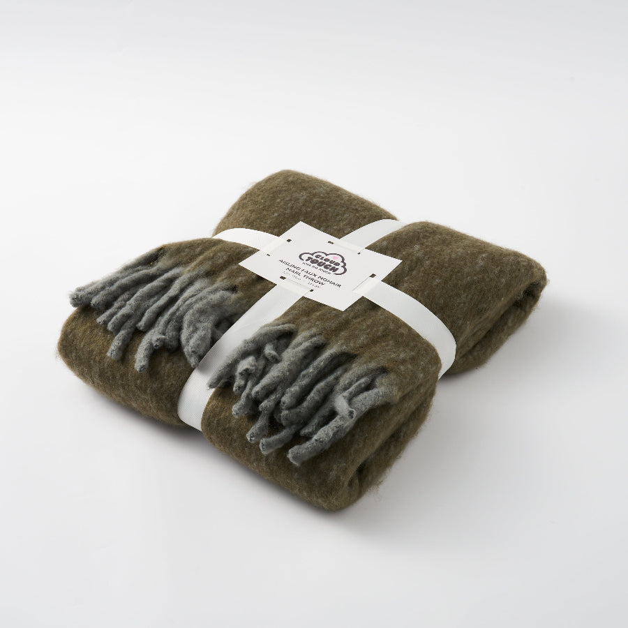 Earthy green blanket with tassels made from faux mohair.