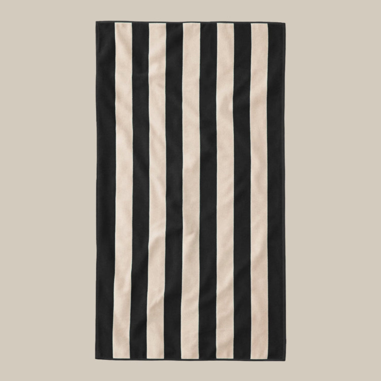 Striped beach towel with black and beige vertical stripes on a beige background