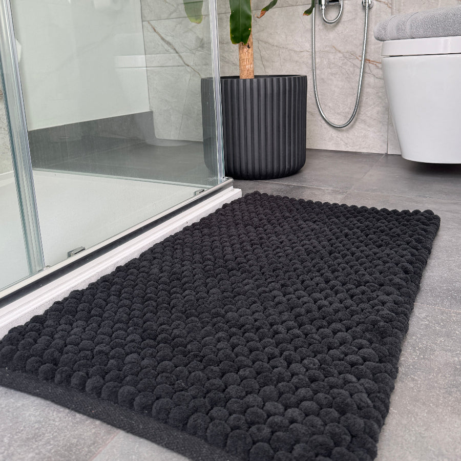 Black bath mat with textured bobble design. Thick and plush deep pile rugs for the bathroom.