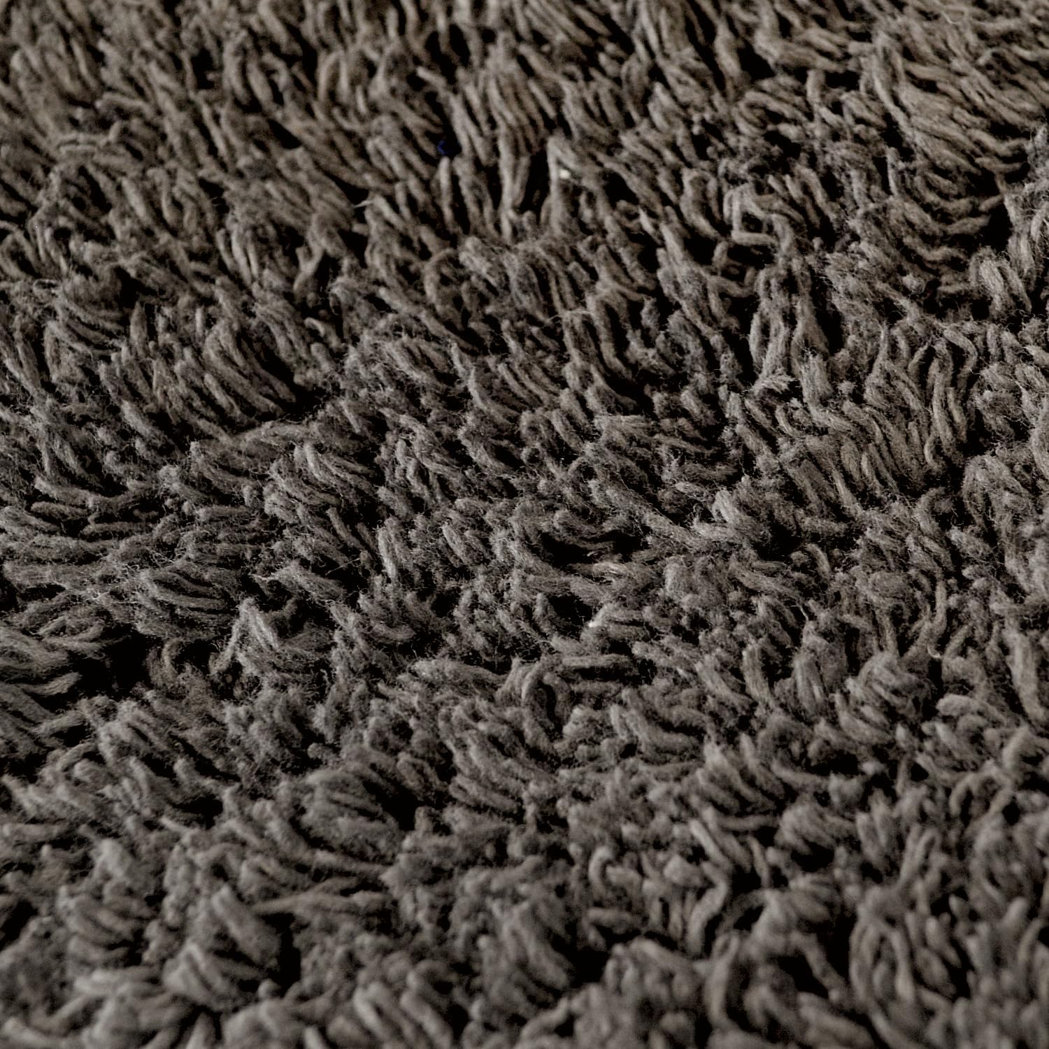 Charcoal grey close up of a cotton bath mat in a curved shape.