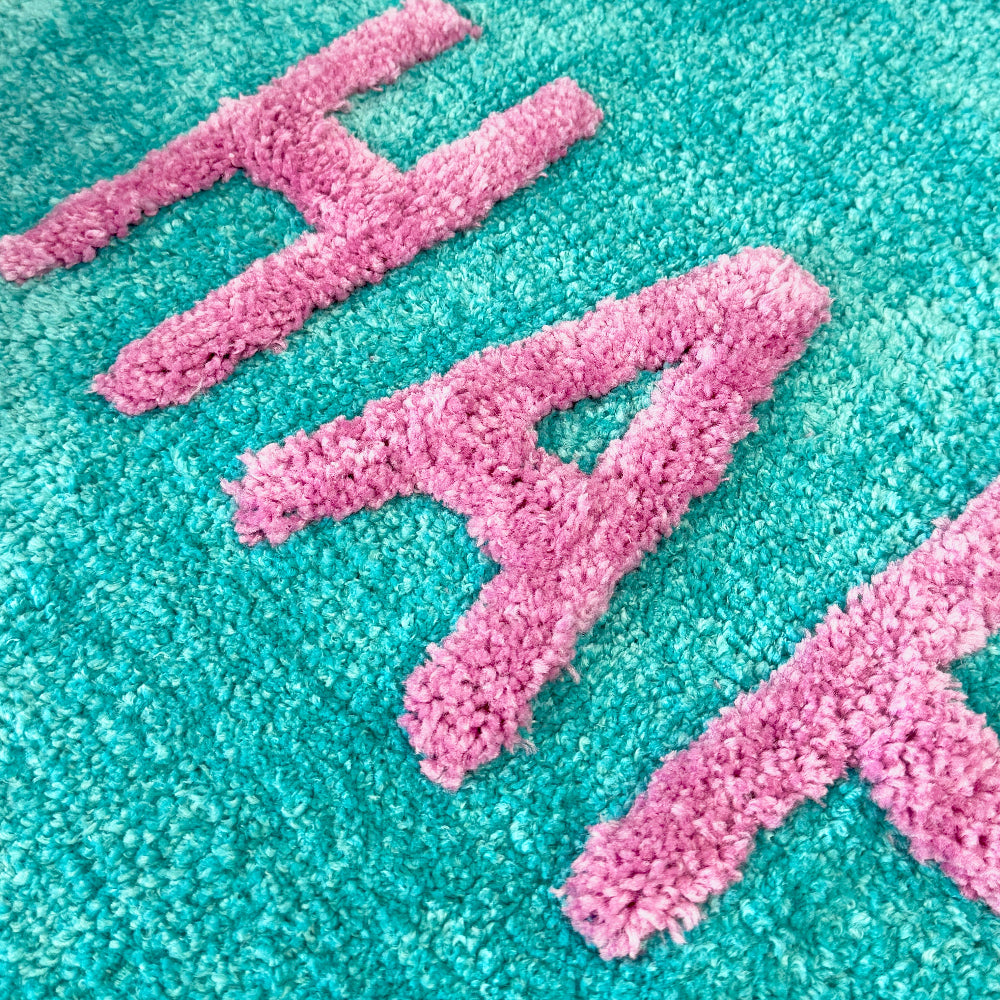 Happy slogan bath mat, turquoise and pink.