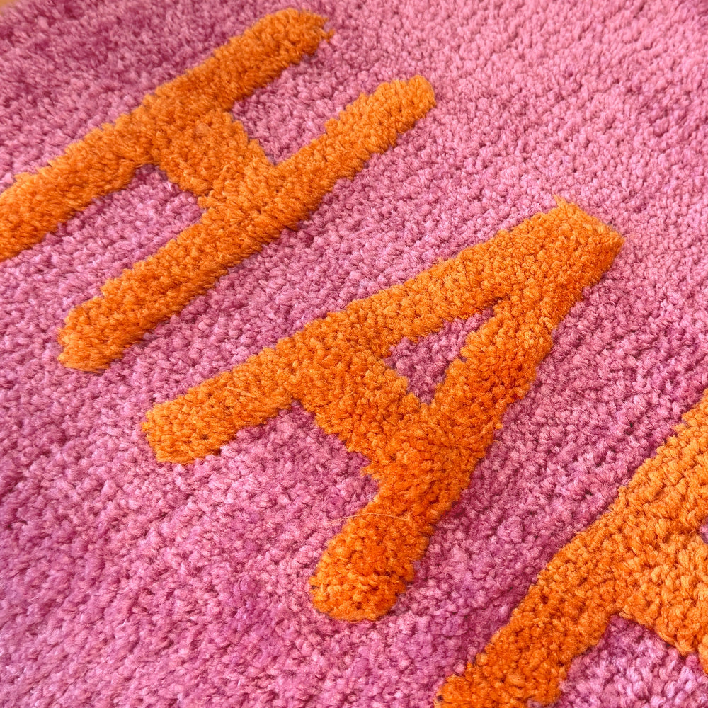 Happy slogan hand tufted bath mat in pink and orange.