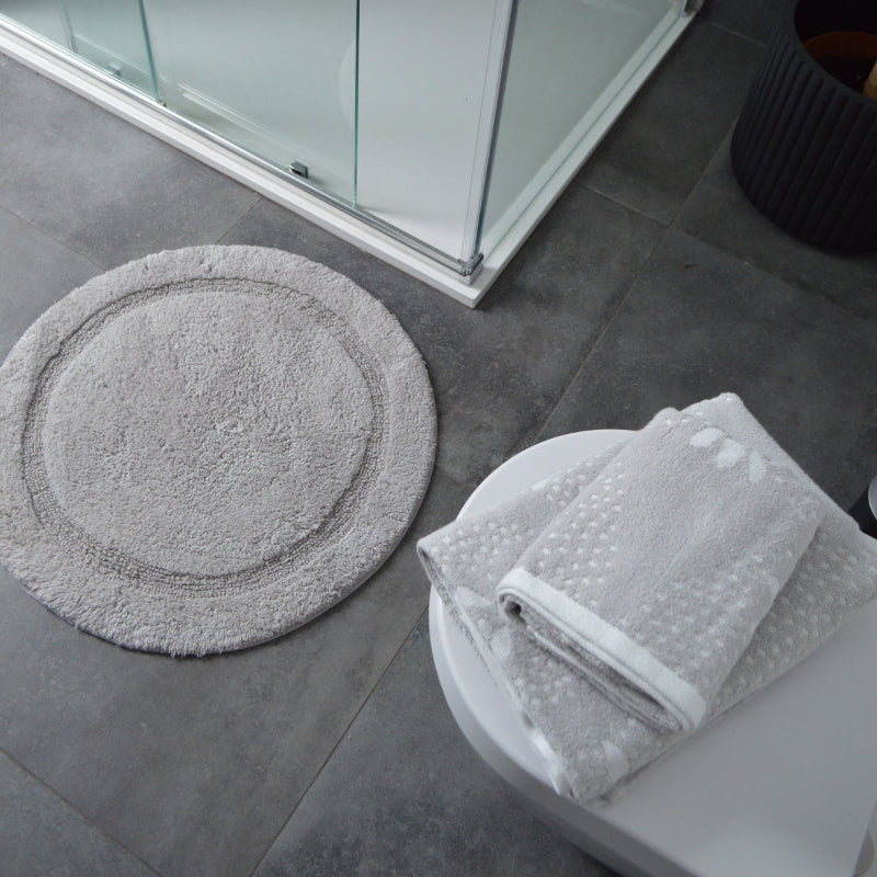 Round bath mat paired with grey patterned towels.