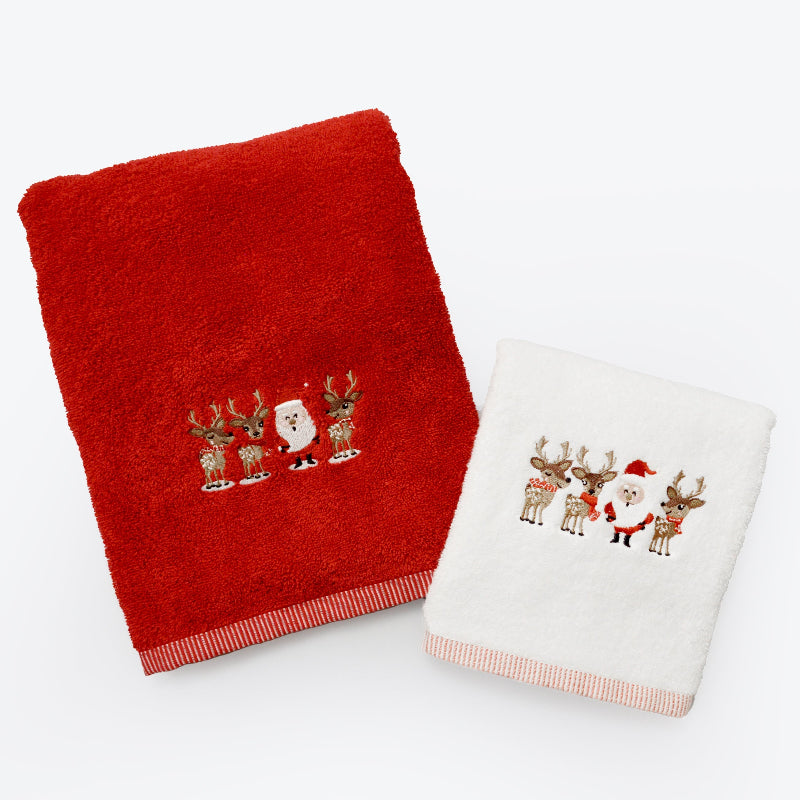 Two embroidered Christmas towels, one red and one white, featuring Santa Claus and reindeer on a white background.