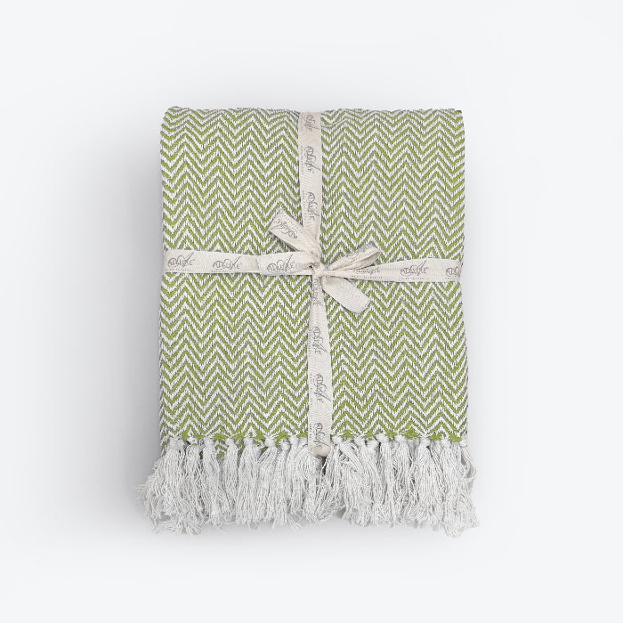 Green patterned blanket with fringe in herringbone chevron design.
