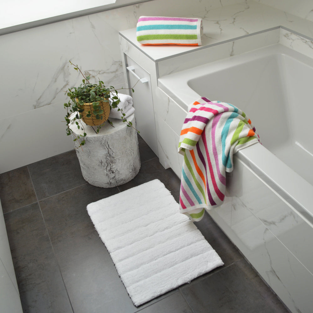 Colourful striped bath towels in rainbow pattern. Blue, orange, pink and green towels in fun maximalist design.
