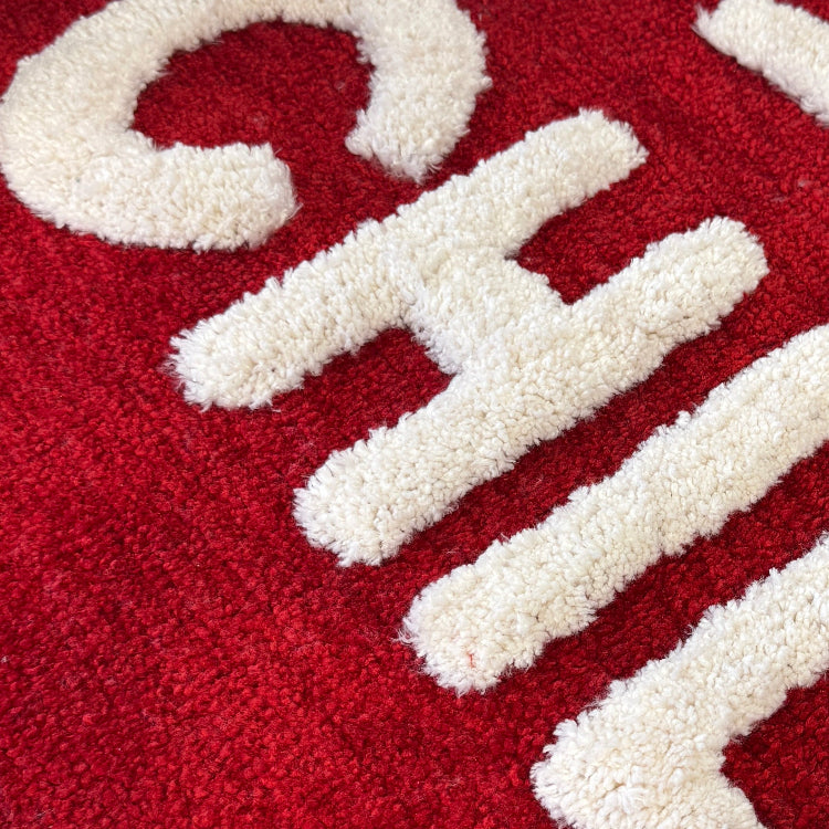 Close-up of a red rug with white text and design.