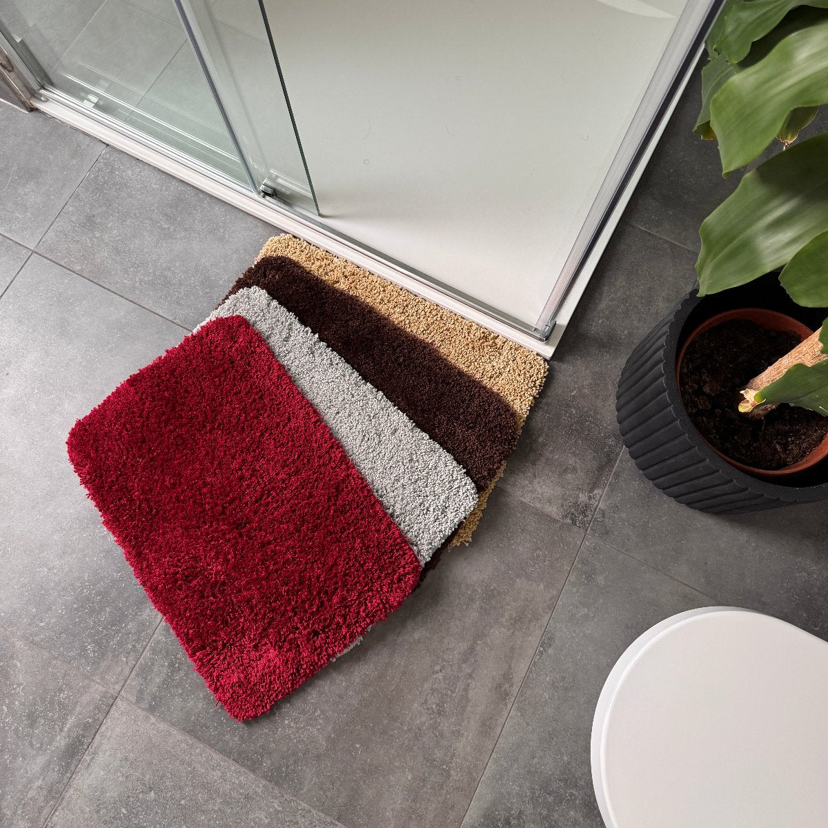 Small bath mats made from microfibre in burgundy, grey, brown and beige.