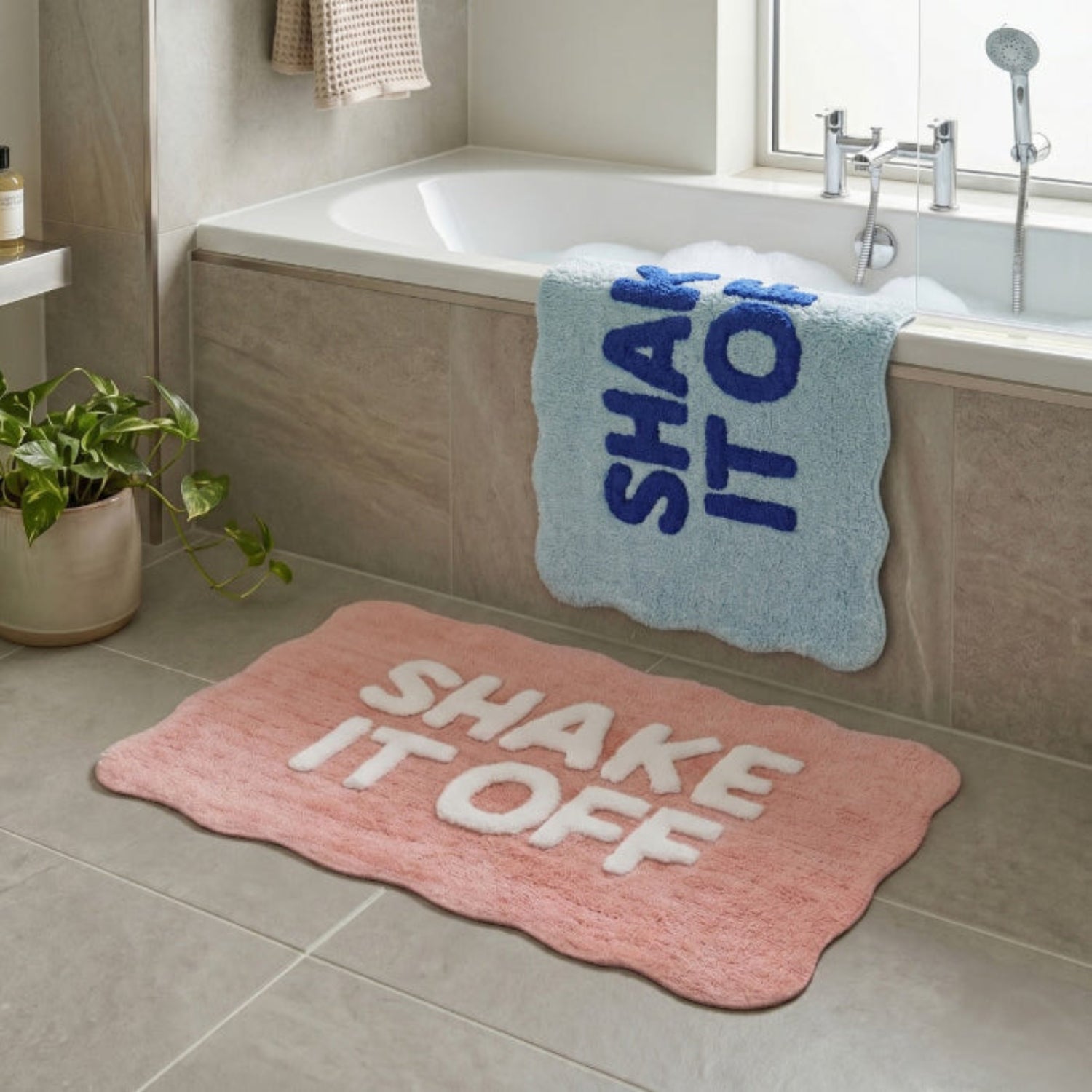 Fun bath mats with shake it off slogan in blue and pink colour options.