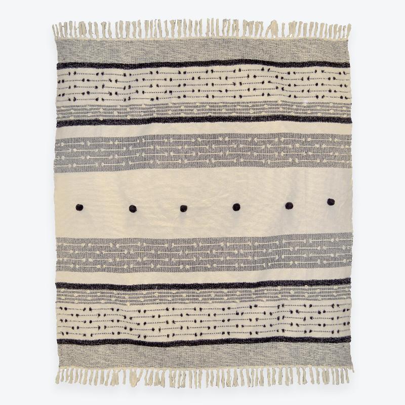 Nina monochrome throw with pom poms and tasselled fringe.