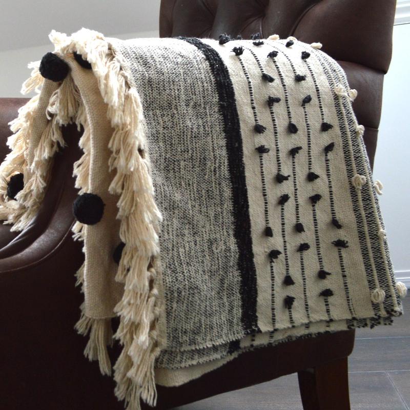 Cream and black textured throw with pompoms.