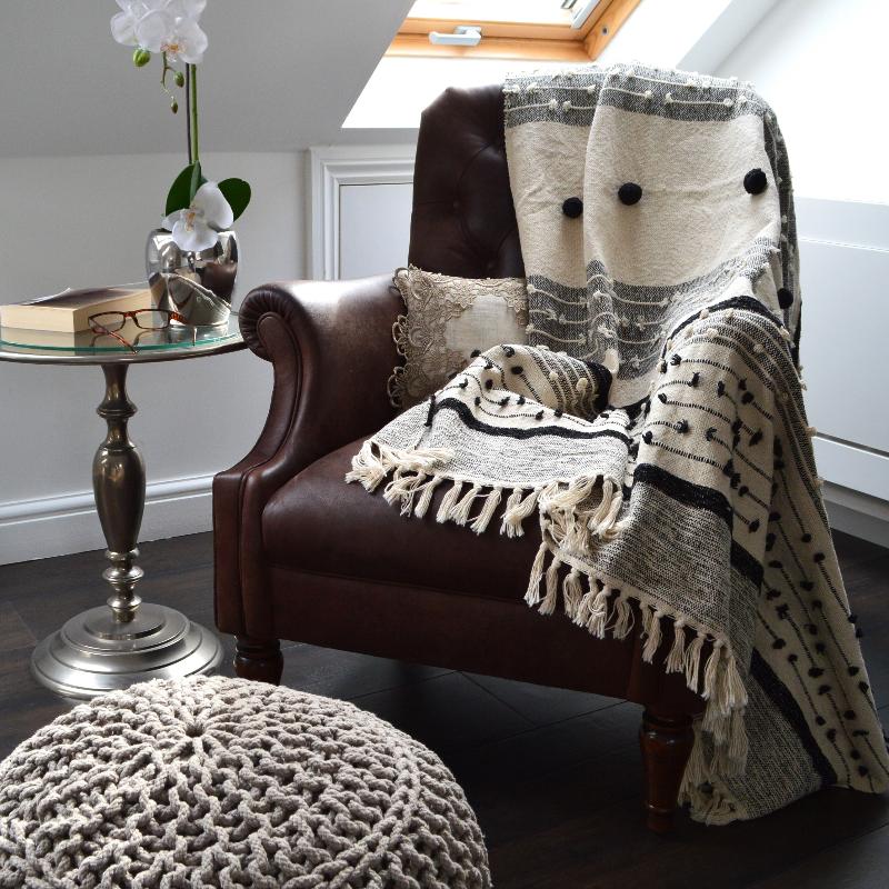 Decorative, boho, patterned throw with pom poms for an arm chair.