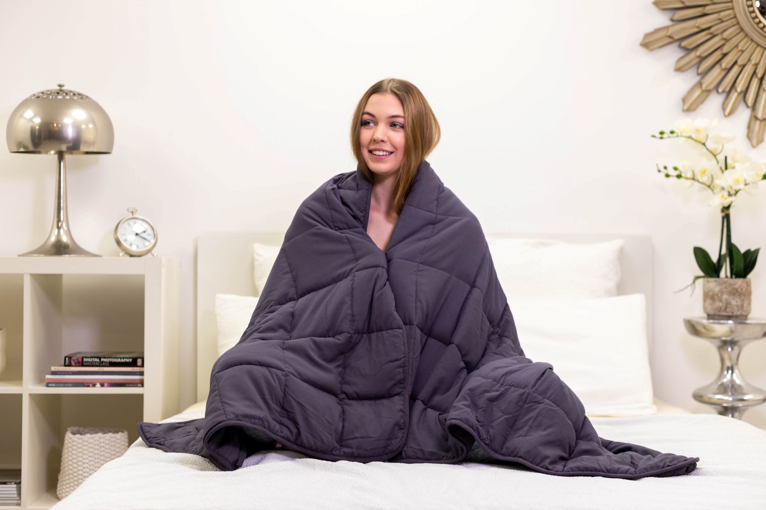 a smiling woman wrapped in a weighted blanket