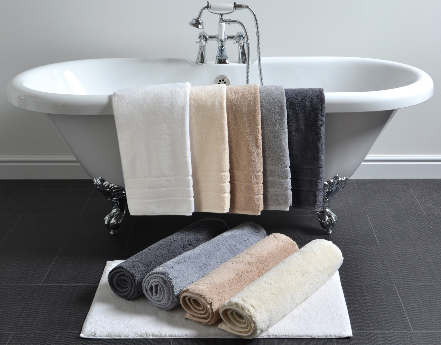 thick towels and bath mats around traditional bathtub