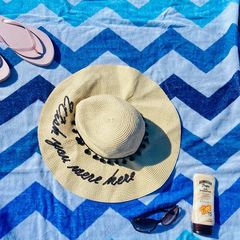 Blue Chevron Beach Towel with Flip flops, sun hat, sunglasses and sun cream on towel