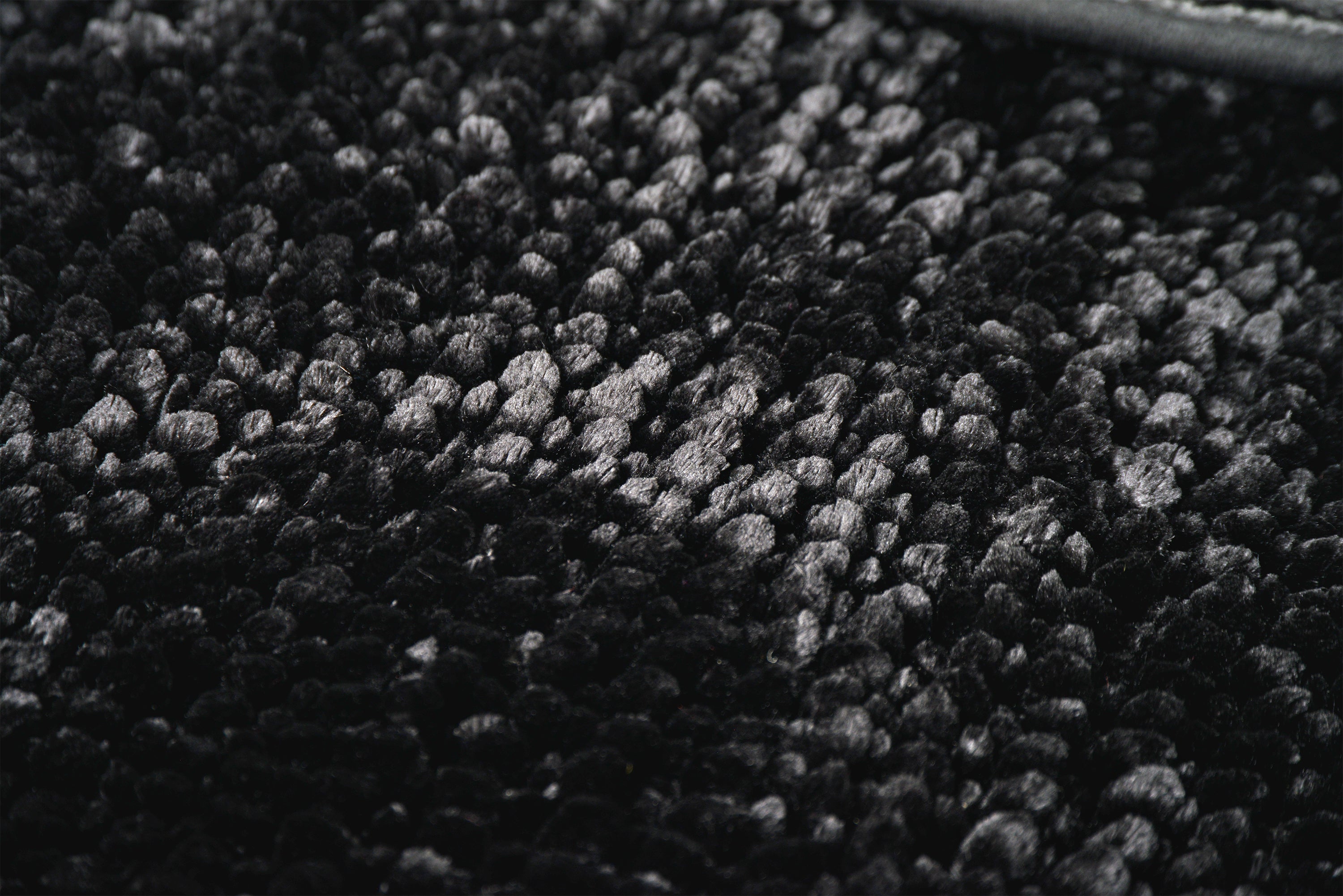 A close up of a black bobble bath mat
