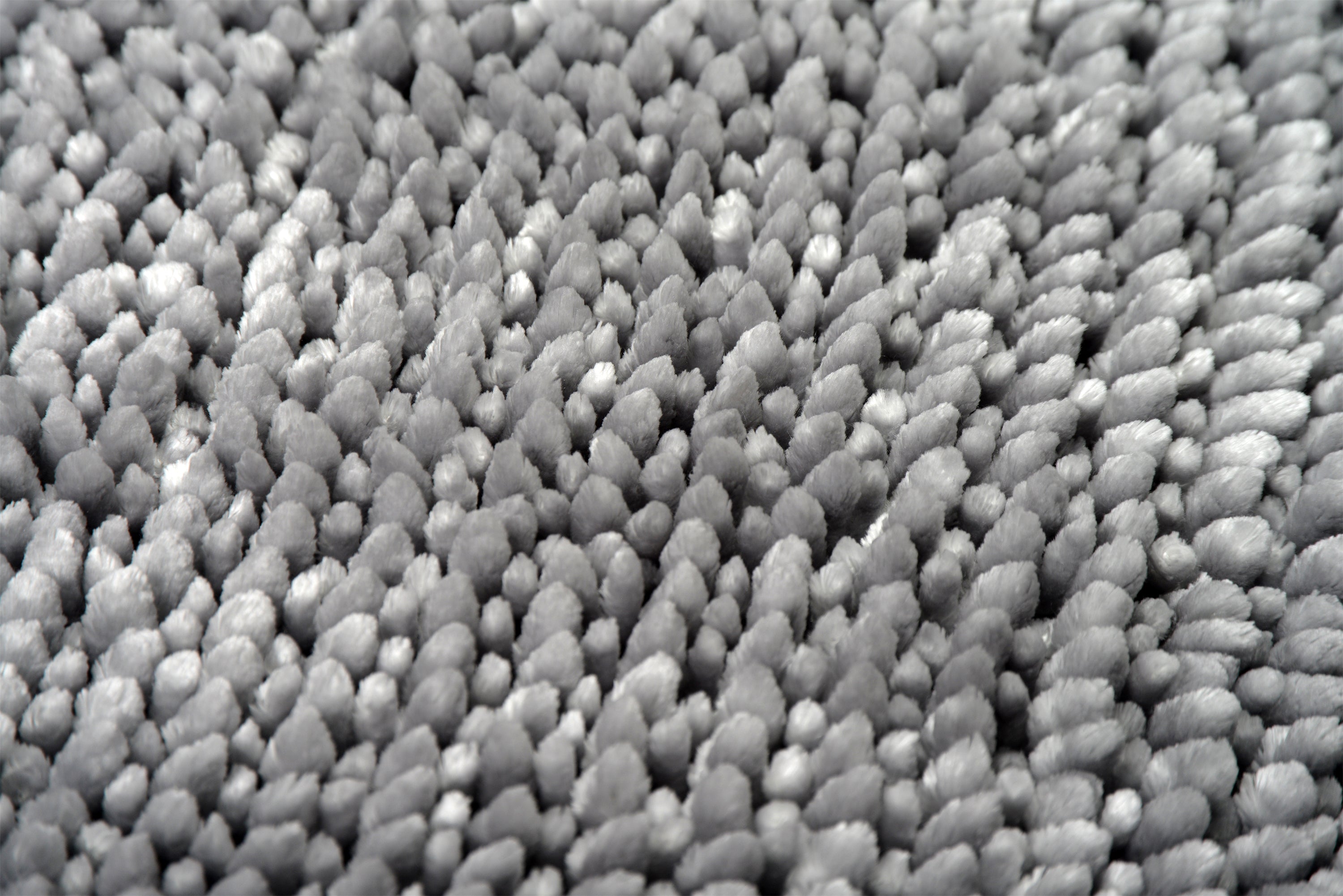A close up of a light grey bobble bath mat