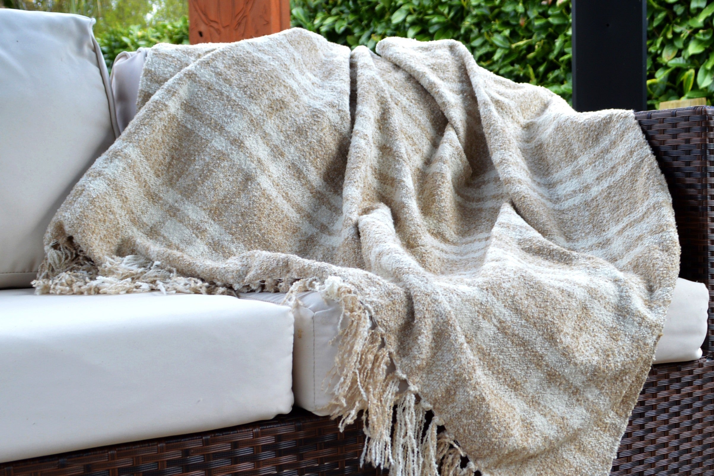 darwin tartan throw natural draped over a sofa in the garden