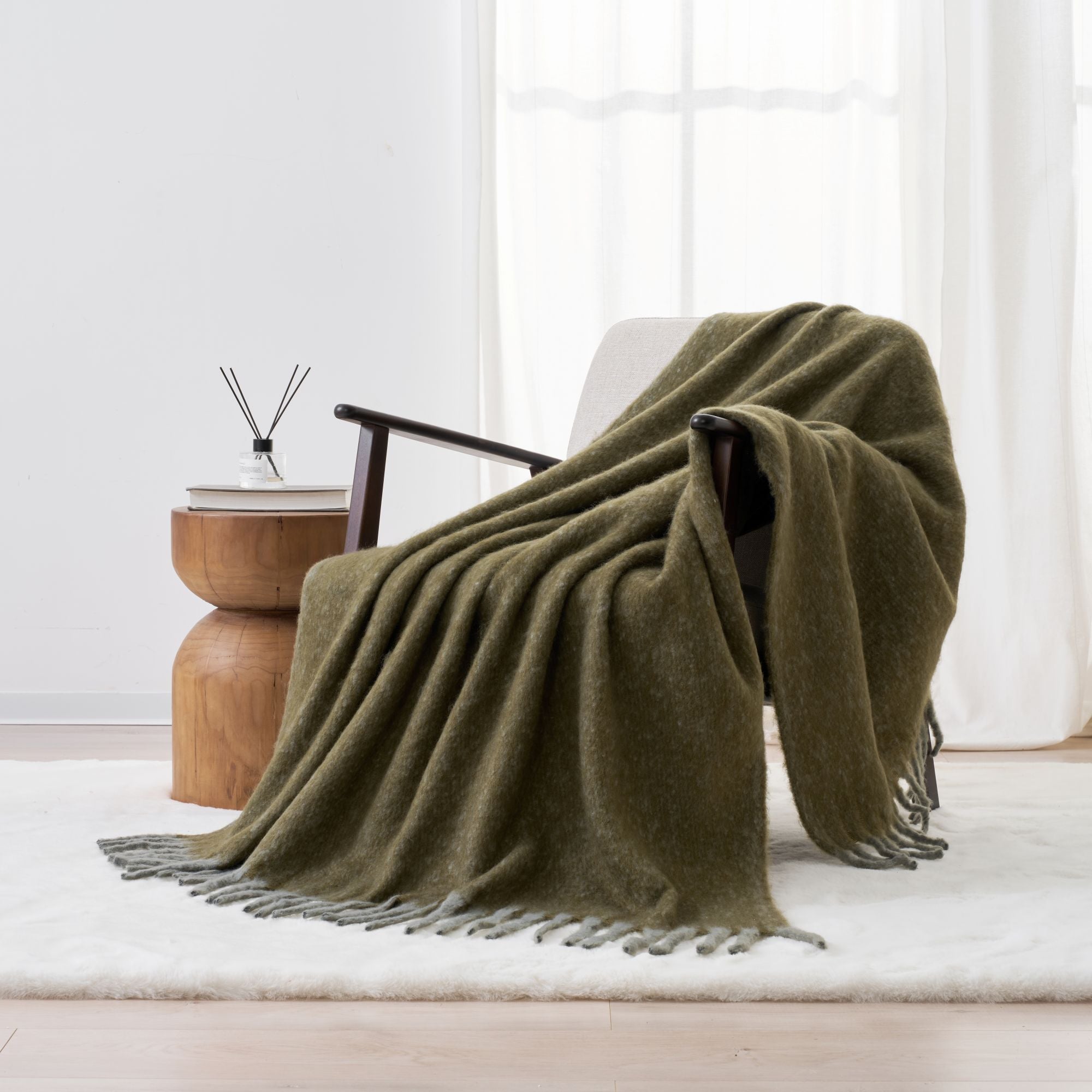 Green blanket with fringe draped over a chair. Super soft faux mohair material.