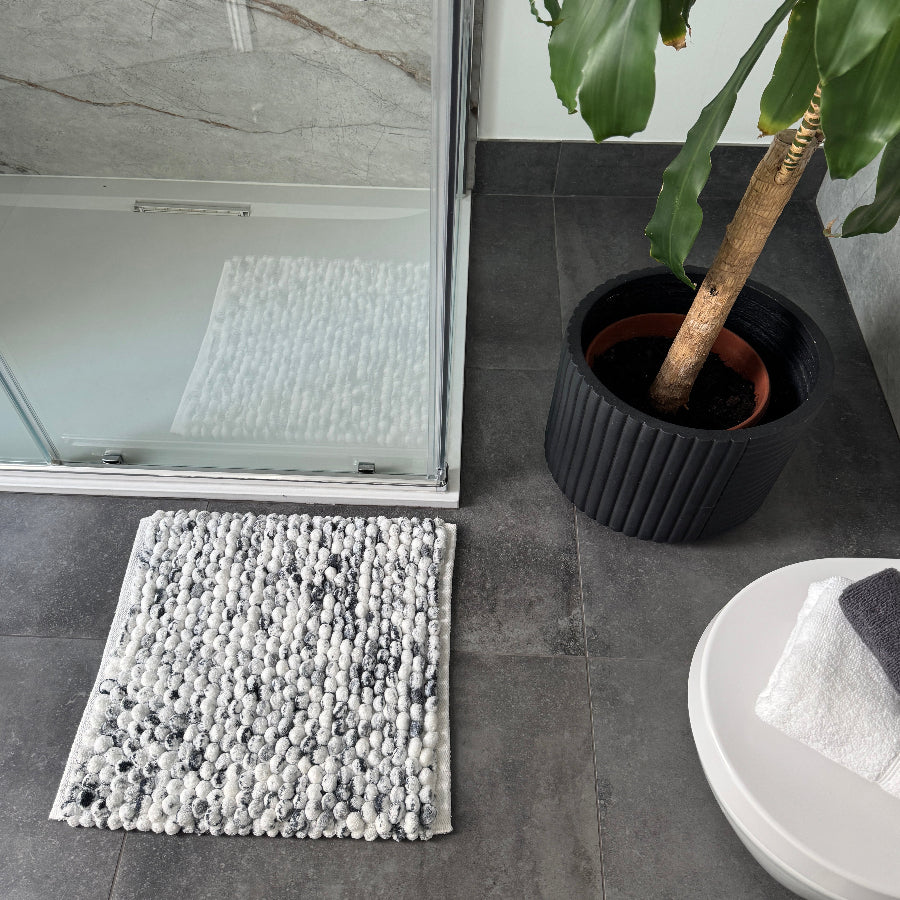 Black and white square bath mat in marble pattern.