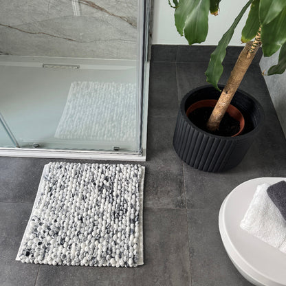 Black and white square bath mat in marble pattern.