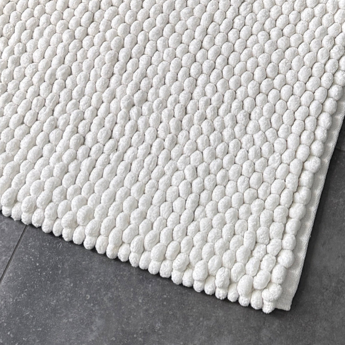 Plain white chunky bobble bath mat with thick handwoven pompom design. 