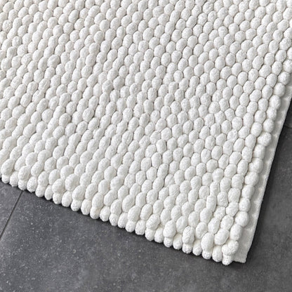 Plain white chunky bobble bath mat with thick handwoven pompom design. 