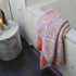 Patterned mandala towel in lilac and coral colours - textured jacquard design.