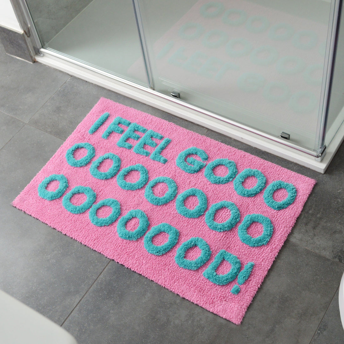 Pink bath mat with blue slogan design, I feel good. 