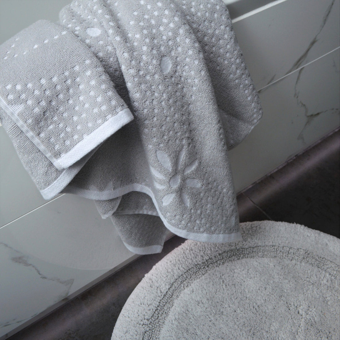 A Marrakesh Bath Towel hung over the edge of a bathtub