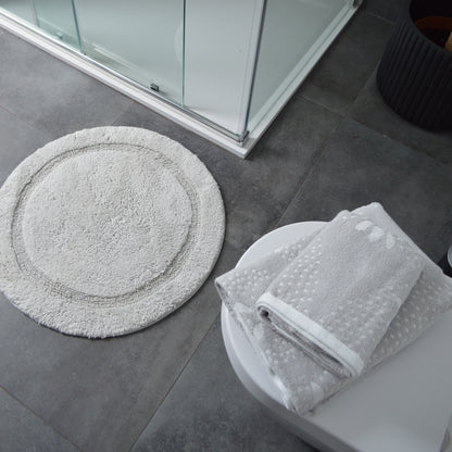 Round bath mat paired with grey patterned towels.
