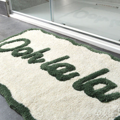 Green and cream scalloped bath mat with hand tufted slogan.