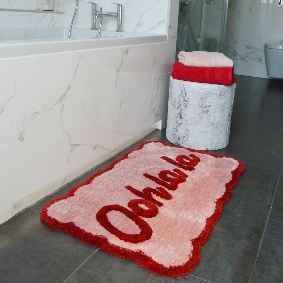 Pink and red slogan bath mat, Ooh la la. Scalloped edges.