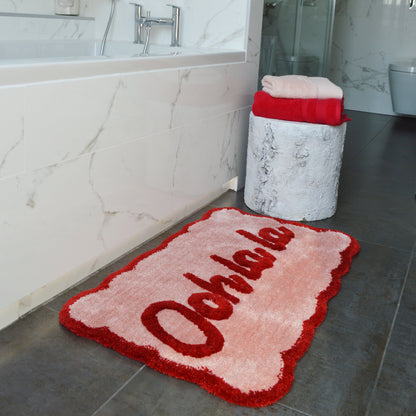 Pink and red slogan bath mat, Ooh la la. Scalloped edges.