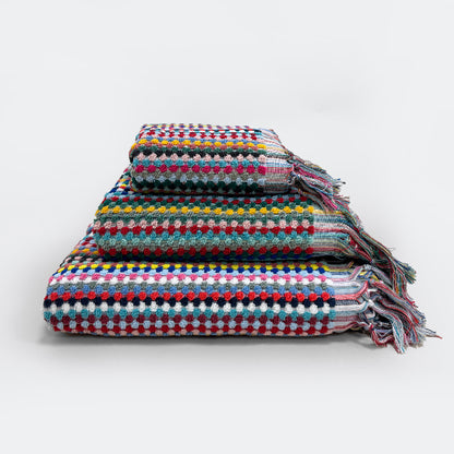 Set of colourful patterned towels for the bathroom in three sizes: hand towel bath towel and bath sheet.