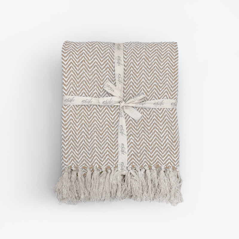 Beige throw blanket in herringbone chevron pattern. Neutral cotton throw for the sofa.