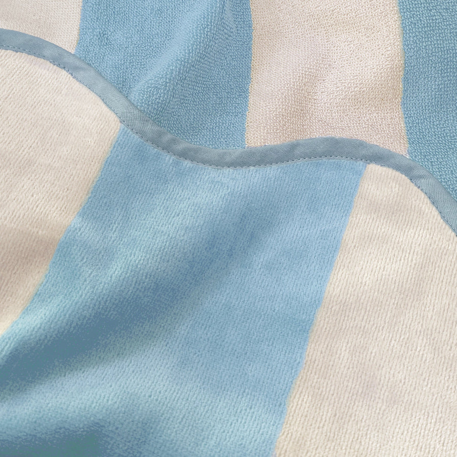 Close up of striped reversible beach towel with terry cloth and velour feel, baby blue colour.