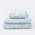 Set of towels for the bathroom with textured floral pattern - hand towel, bath towel and bath sheet in baby blue colour.