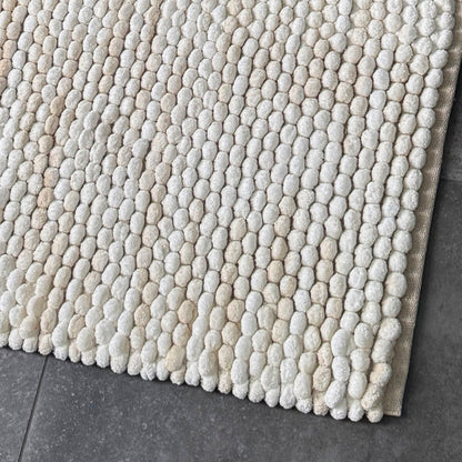 Cream and beige bath mat is marble pattern, handwoven deep pile bobbles.