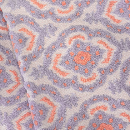 Close-up of cotton towel with a mandala pattern of pink and purple shapes on a white background.