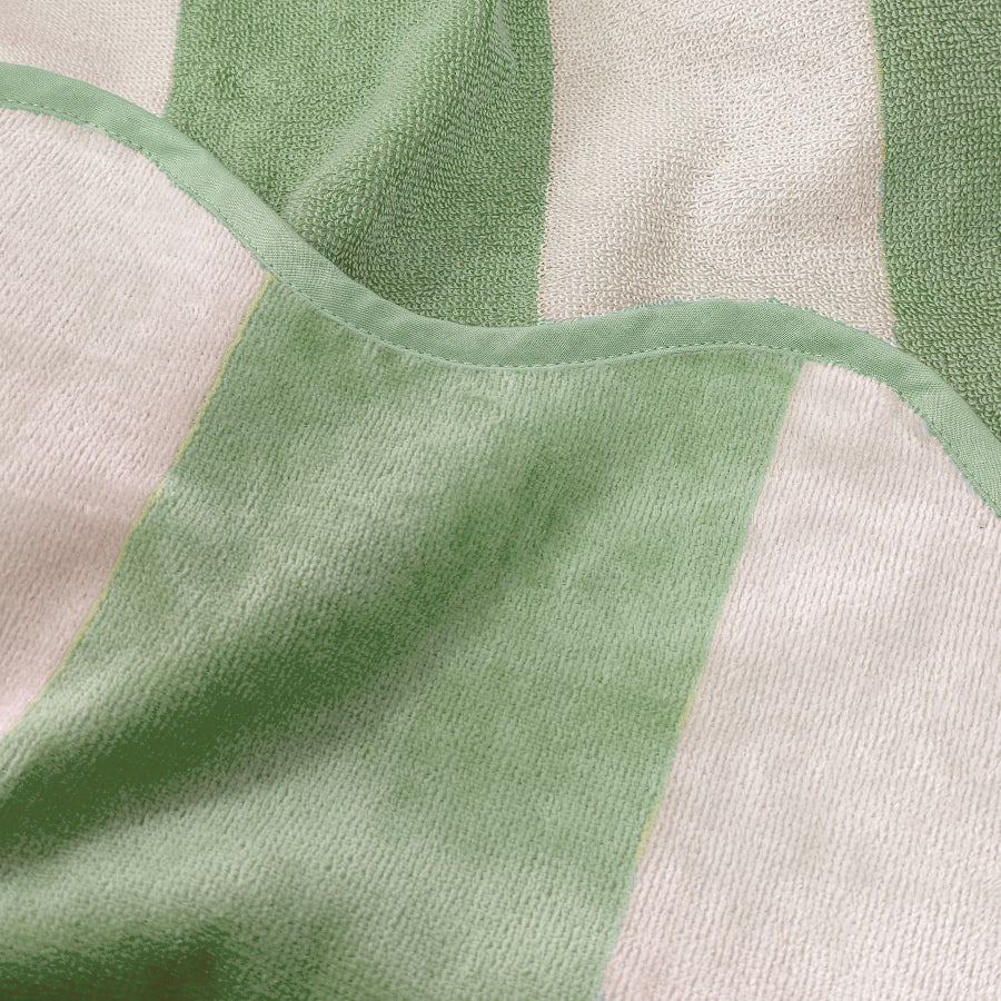 Close up of striped reversible beach towel with terry cloth and velour feel, pale green colour.