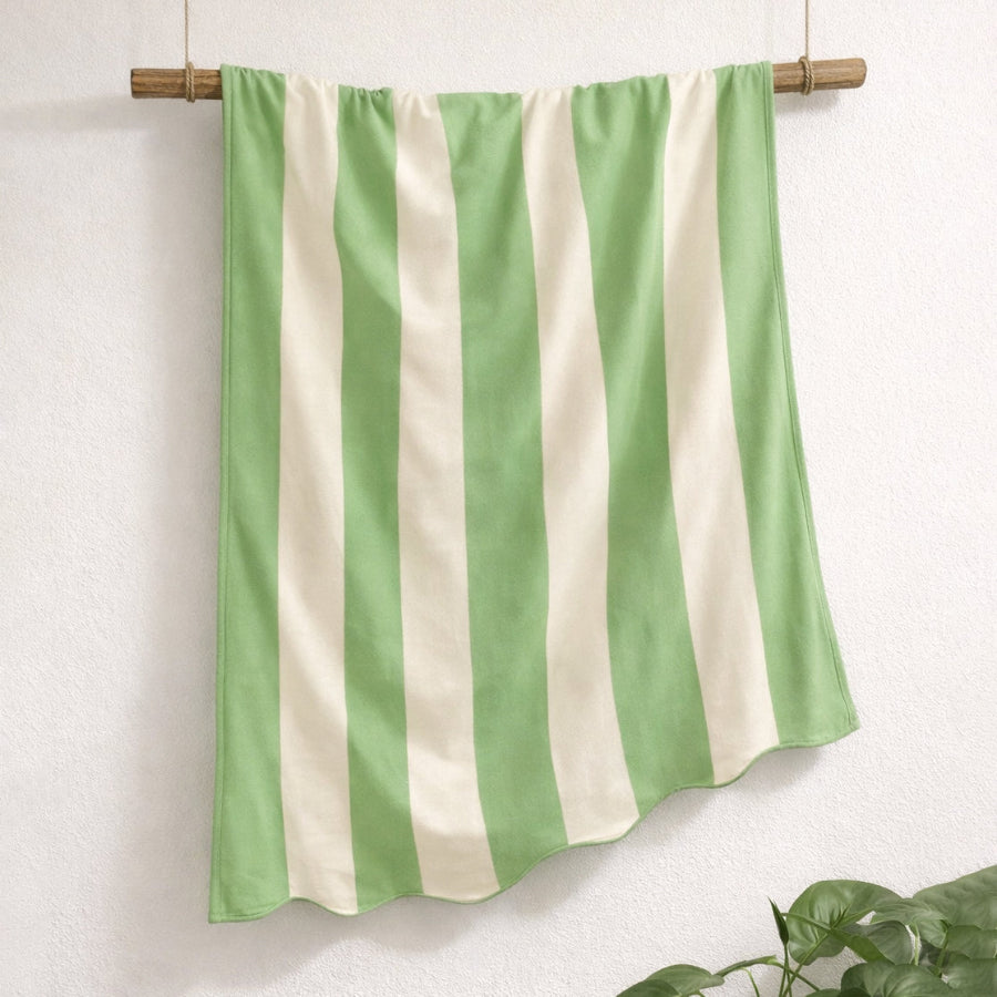Green and white scalloped beach towel in striped pattern, made from cotton.