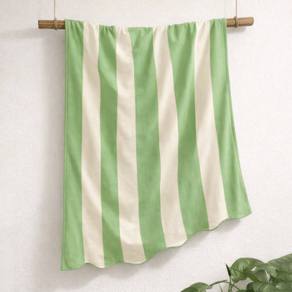 Green and white scalloped beach towel in striped pattern, made from cotton.