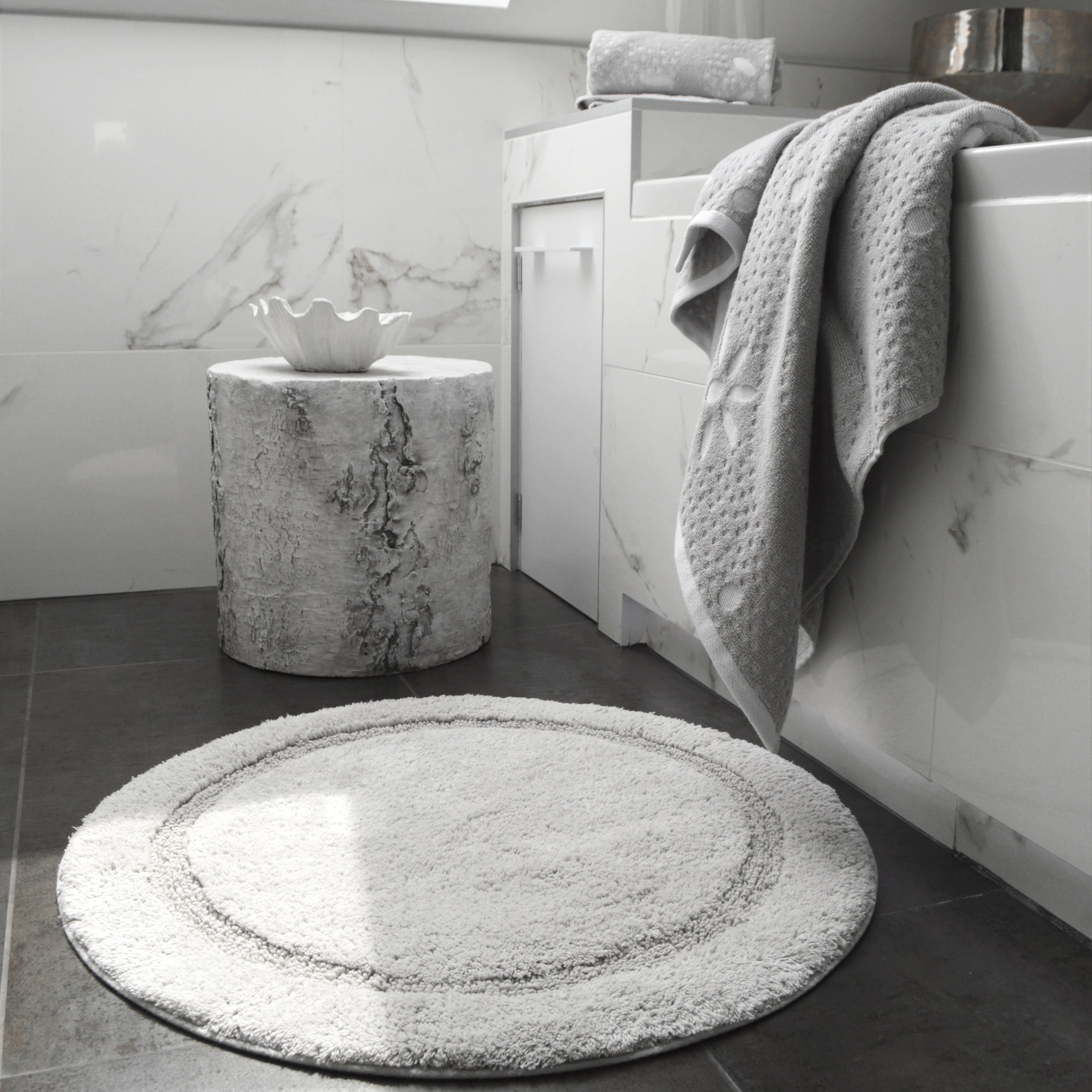 Dove grey round bath mat and co-ordinating towels.