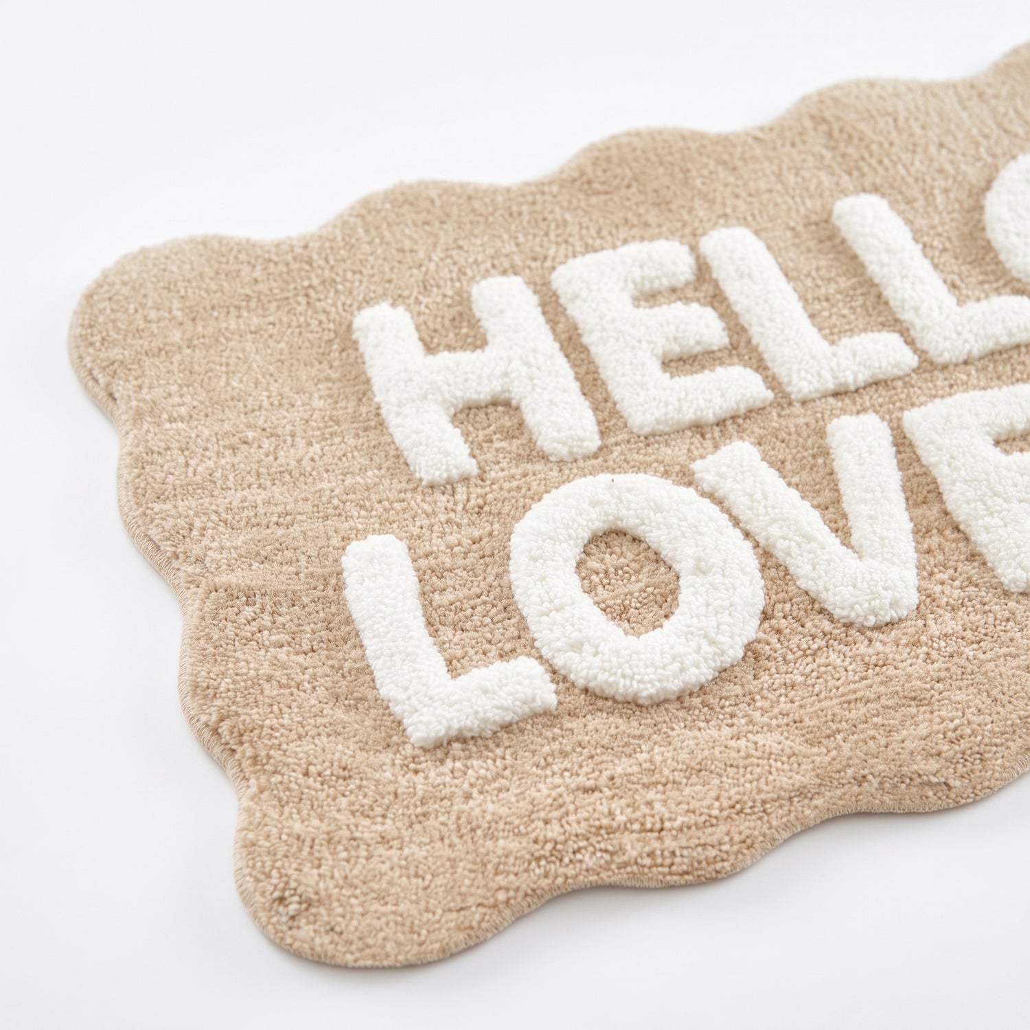 Hello lovely slogan bath mat in beige and white - fun scalloped edging.