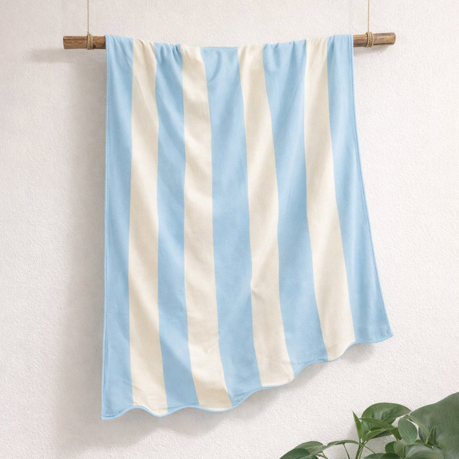 Blue and white striped beach towel with scalloped edge, made from cotton.