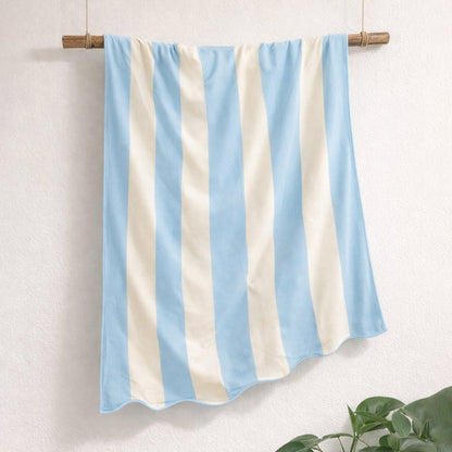 Blue and white striped beach towel with scalloped edge, made from cotton.