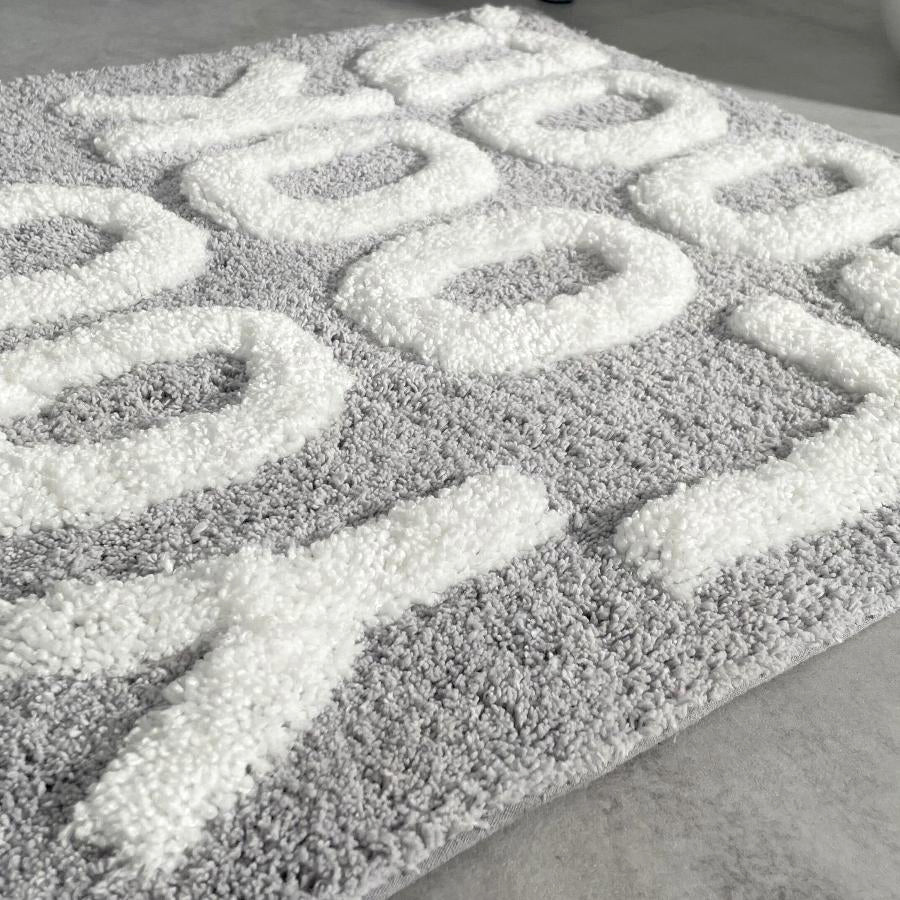 You look good hand tufted slogan bath mat in grey and white.