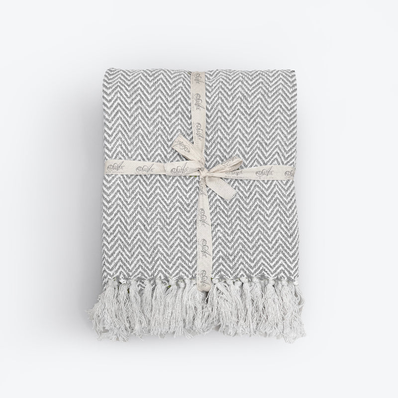 Off white and grey herringbone blanket made from cotton. White chevron throw with tassels. 